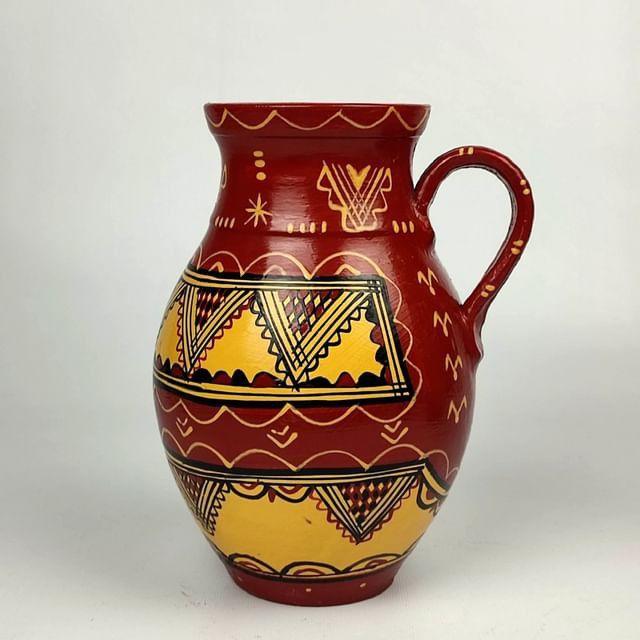 Handmade terracotta vessel, woven textile, and hammered brass in an Algerian workshop